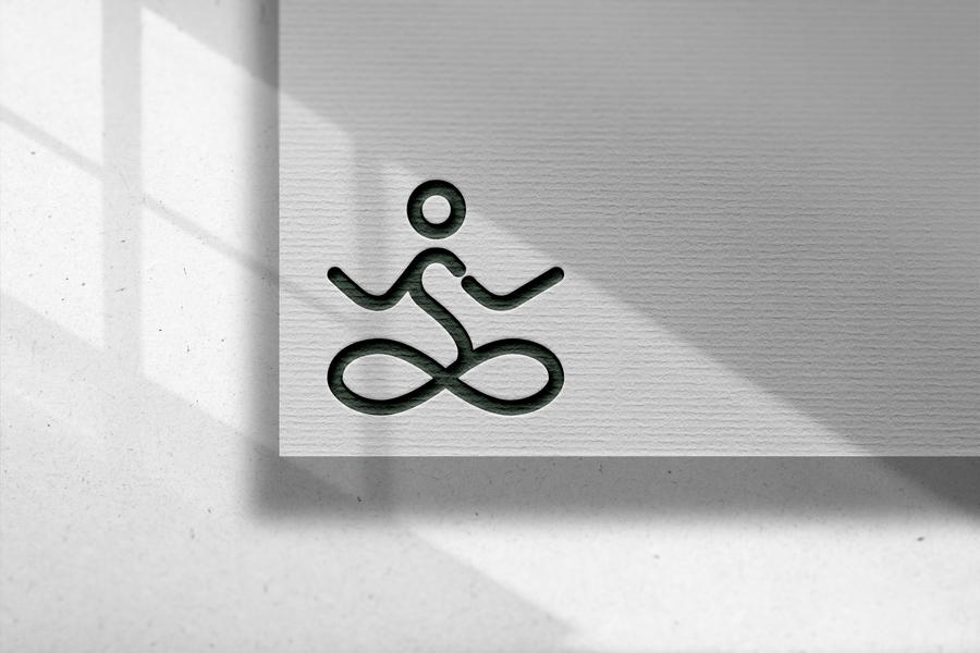 The SoulCheck meditating-figure mark debossed in dark green on textured white paper, lit by window shadows