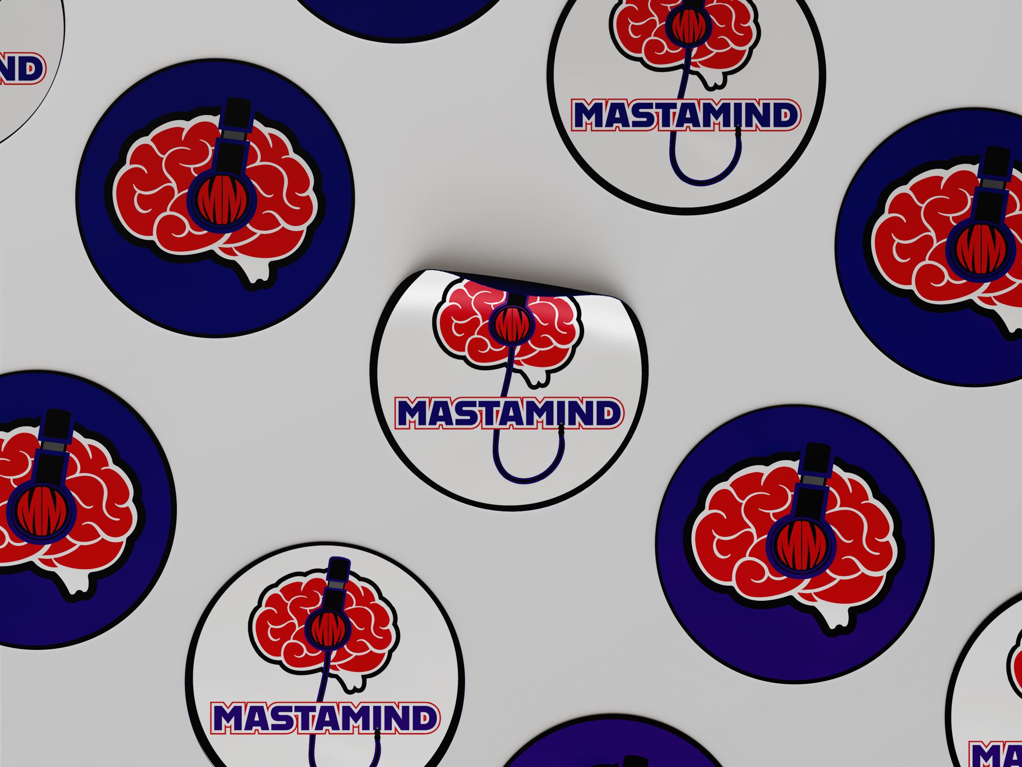Round Mastamind stickers scattered on a gray surface: the red brain with purple headphones on navy circles, and the full logo with the MASTAMIND wordmark on white circles